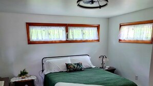A bedroom with a bed, a bedside table, a lamp, and a window with curtains.