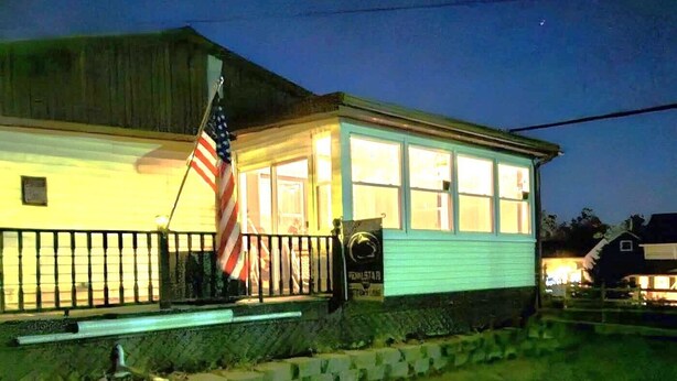 A two-story building with a porch, an American flag, and a sign that reads "DENTAL STUDIO."