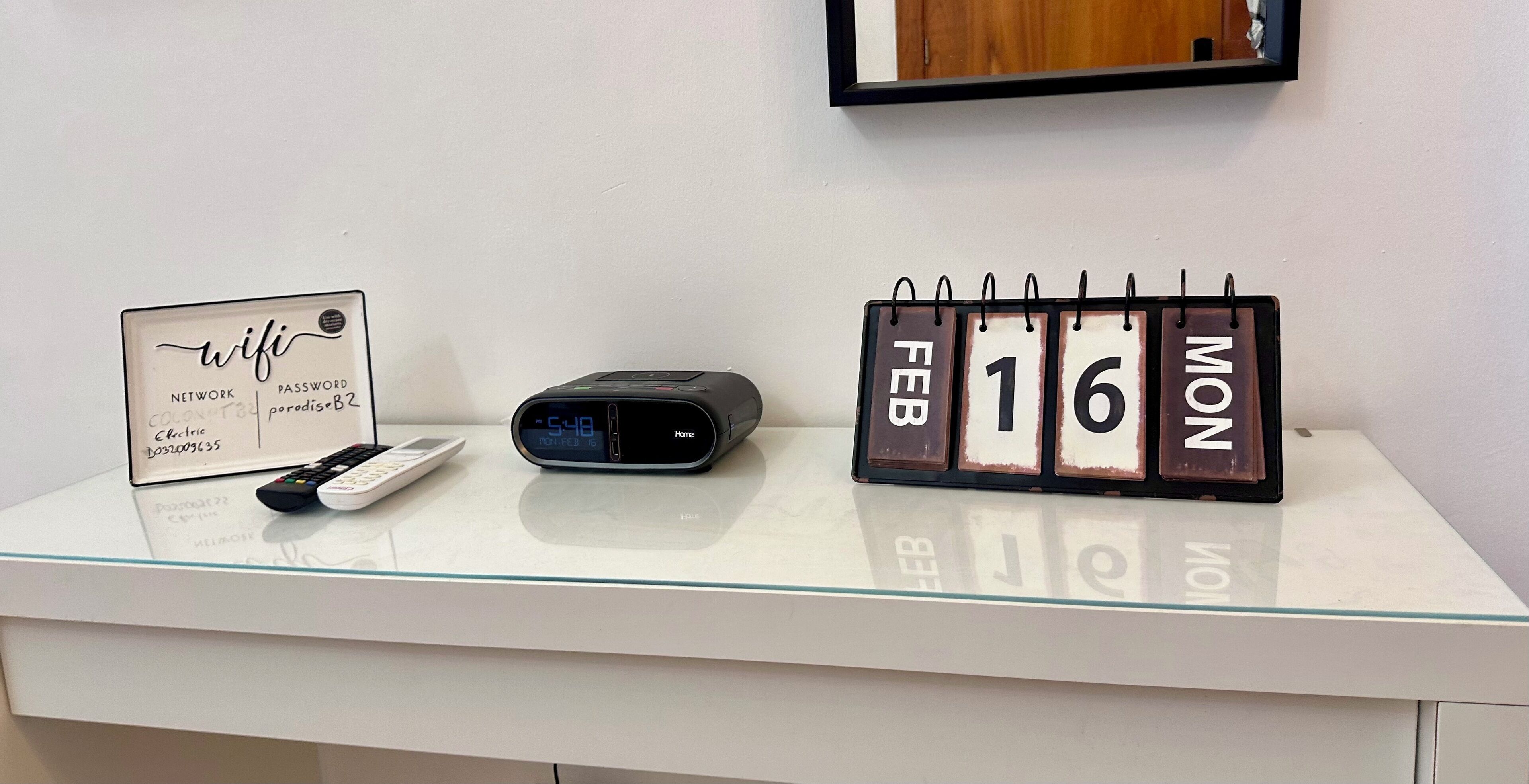 Een bureau met een bord waarop wifi-netwerkinformatie staat, een digitale klok en een kalender met de datum.