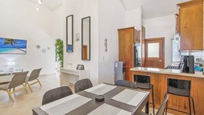 Una cocina moderna con armarios de madera, un comedor con mesa y sillas, y una encimera con una cafetera.
