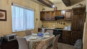 Una cocina con armarios de madera, estufa a gas y una mesa de comedor preparada para cuatro.