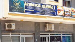 A hotel facade with a signboard advertising services like hotel, restaurant, and parking. - Hospedaria RaSimão 1 (Benguela)