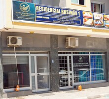 Fachada de hotel com uma placa anunciando serviços como hospedagem, restaurante e estacionamento.