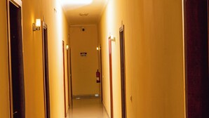 A hotel hallway with doors on both sides, a fire extinguisher on the wall, and a sign above the doors. - Hospedaria RaSimão 1 (Benguela)