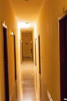 Corredor de hotel com portas em ambos os lados, um extintor de incêndio na parede e uma placa acima das portas.
