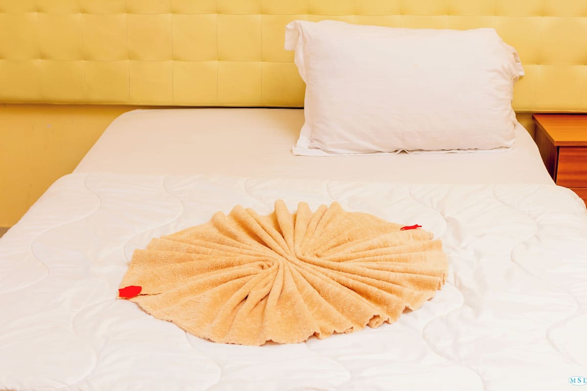 Una cama con colchón blanco y cabecera amarilla.