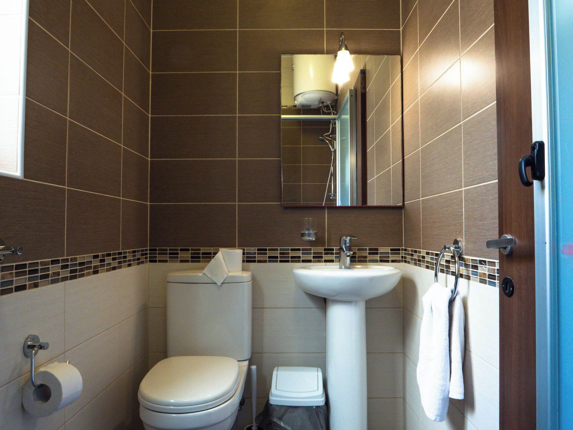 A bathroom with a toilet, sink, and mirror.