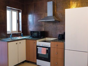 Eine kompakte Küche mit Mikrowelle, Backofen und integrierter Dunstabzugshaube.