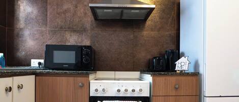 Een keuken met een magnetron, fornuis, oven en koffiezetapparaat.