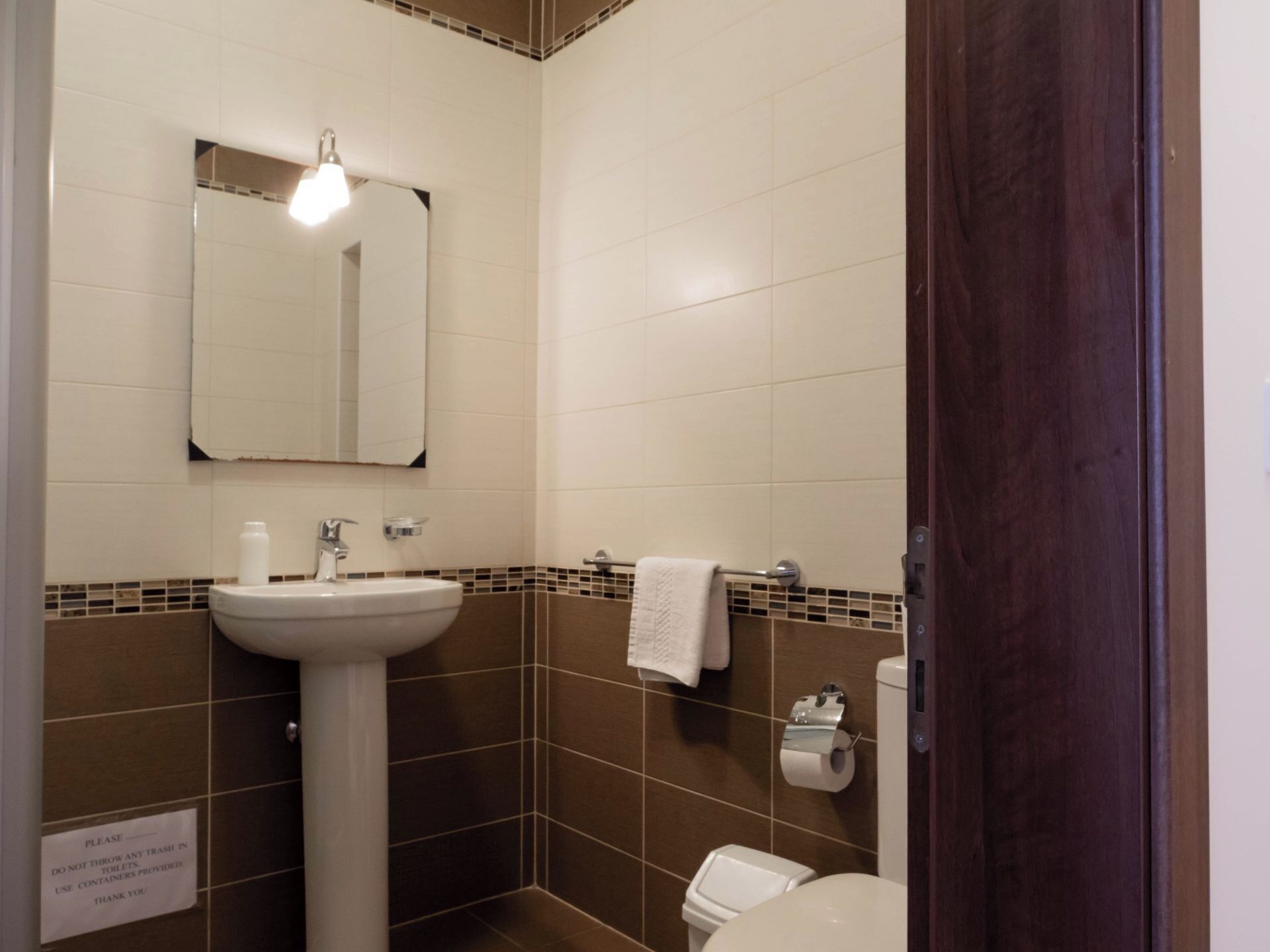 A bathroom with a white sink, a mirror, a towel rack, and a toilet.