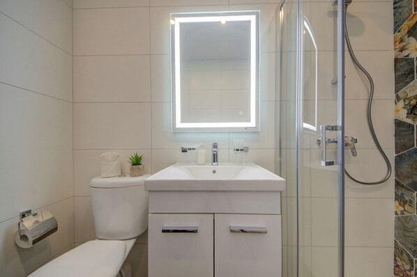 A modern bathroom with a glass shower enclosure, a white sink, and a toilet. - Charming Sliema Apartment Off the Ferries Seafront (Sliema)