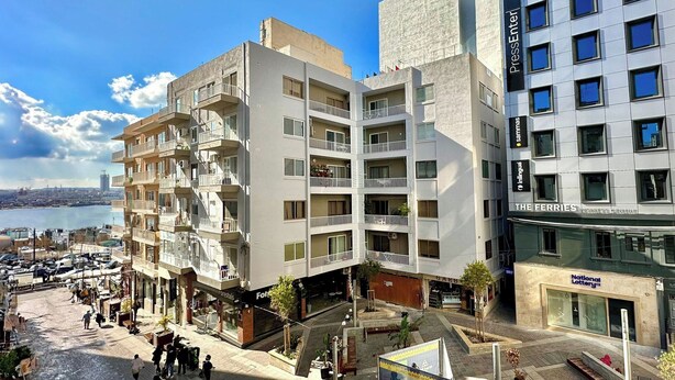 A multi-story building with balconies, a parking lot, and a view of the sea. - Charming Sliema Apartment Off the Ferries Seafront (Sliema)