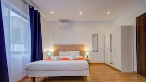 A hotel room with a large bed, wooden flooring, a ceiling air conditioner, and a wardrobe. - Charming Sliema Apartment Off the Ferries Seafront (Sliema)