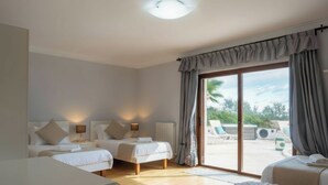 A hotel room with two beds, a large sliding glass door to a balcony, and a view of the outdoors. - Villa Alexandra: Sea Views, Pool, Jacuzzi & Sauna (Mellieha)