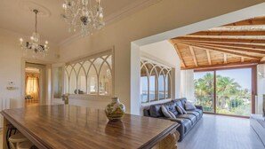 A spacious living area with a wooden ceiling, a large window with a view, and a chandelier. - Villa Alexandra: Sea Views, Pool, Jacuzzi & Sauna (Mellieha)