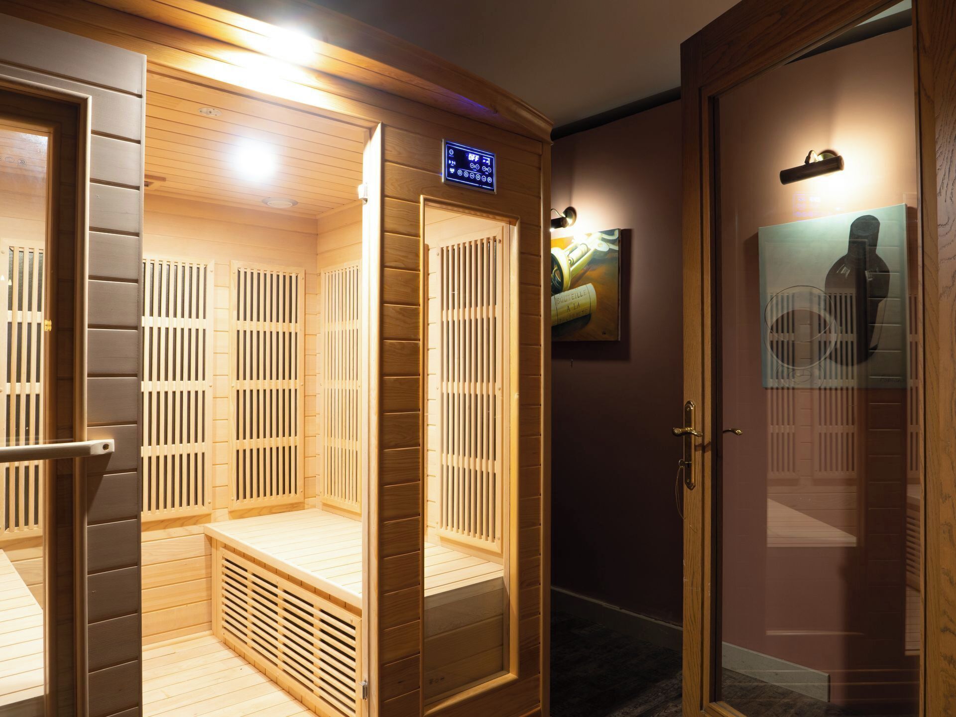A sauna room with wooden benches and a digital control panel.