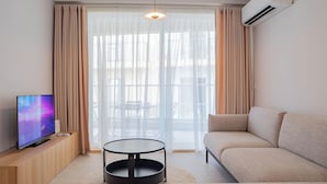A modern living room with a sofa, a round coffee table, and a TV on a wooden cabinet. - Lovely Contemporary Apartment Off St. Julian's (St. Julian's)