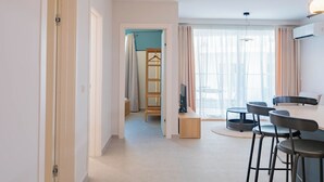 A modern hotel room with a dining area, a TV, and a large window with curtains. - Lovely Contemporary Apartment Off St. Julian's (St. Julian's)