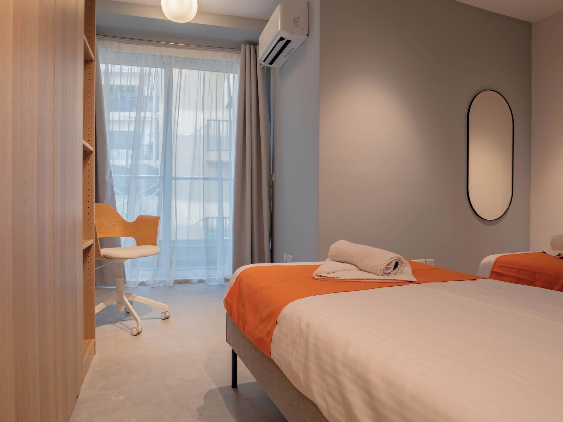 A modern hotel room with a large bed, a chair, and a window with curtains.