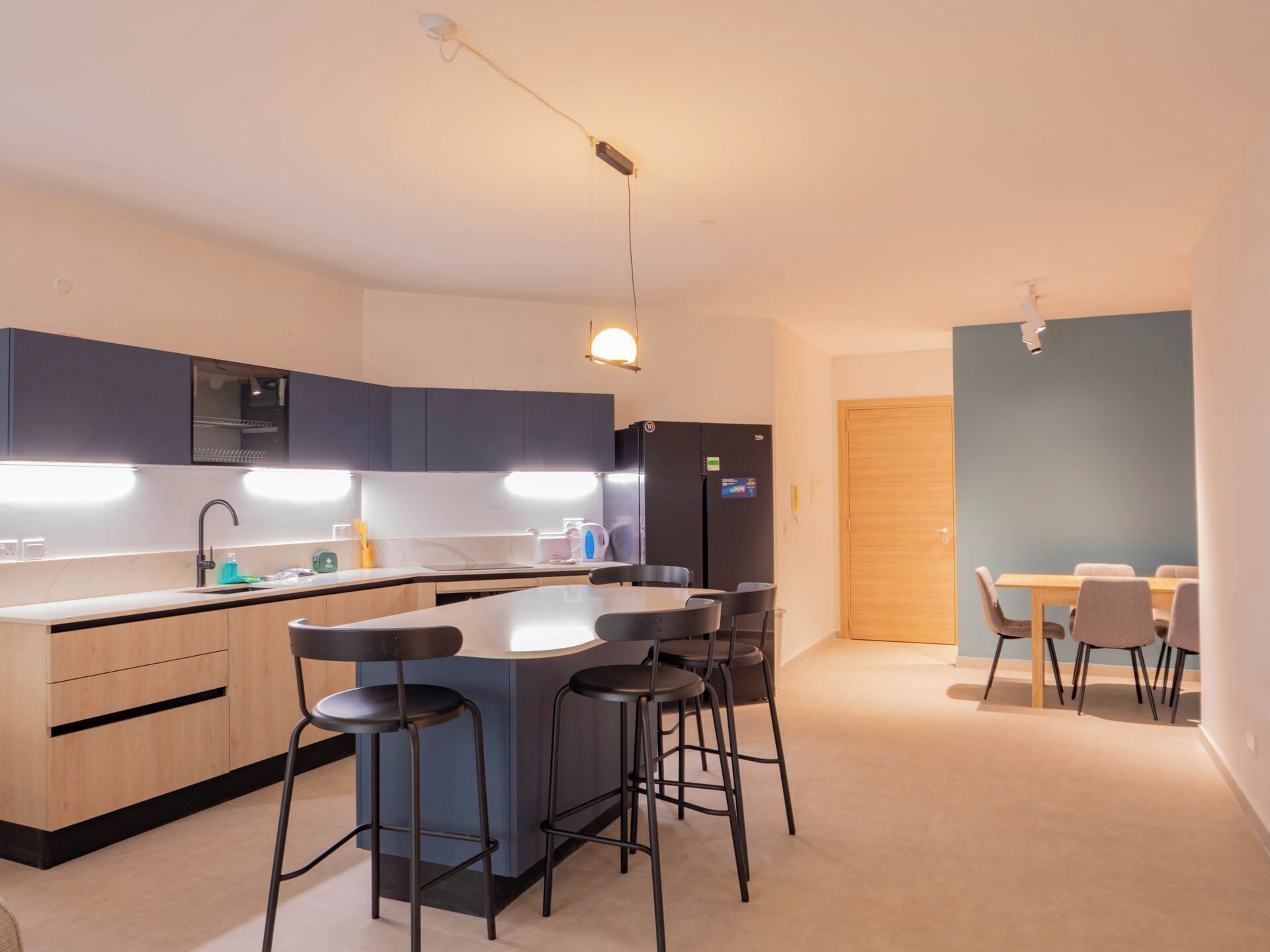Une cuisine moderne dotée d’un îlot central, de tabourets de bar et d’un coin repas avec une table et des chaises.