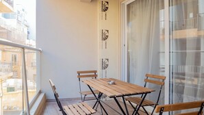 A balcony with a wooden table and chairs, a glass door, and a view of buildings. - Lovely Contemporary Apartment Off St. Julian's (St. Julian's)