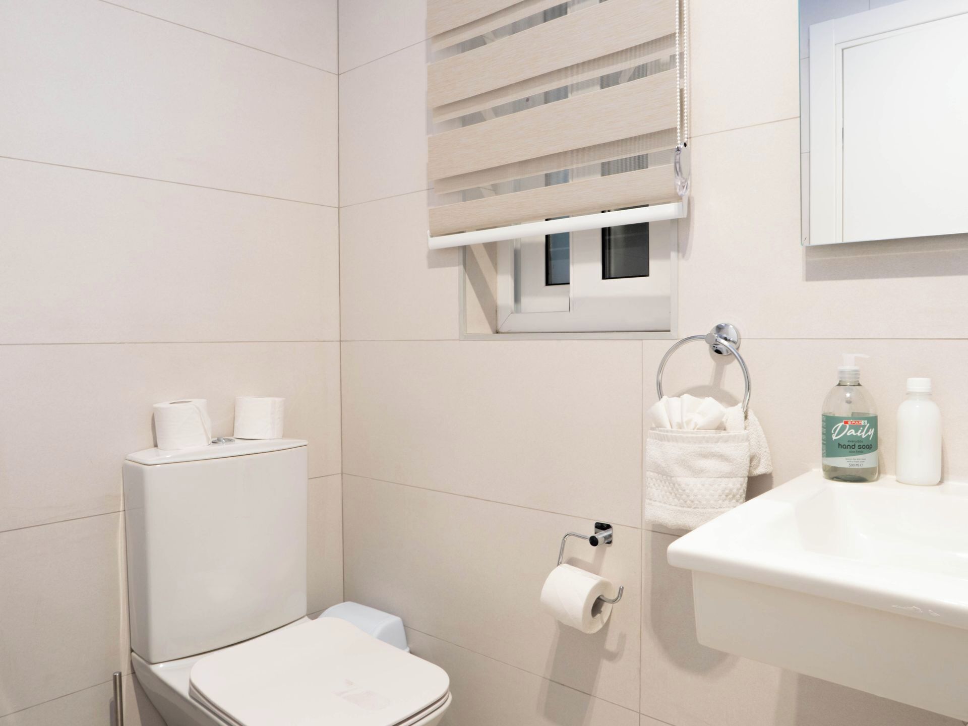 A modern bathroom with a toilet, a sink, and a towel rack.