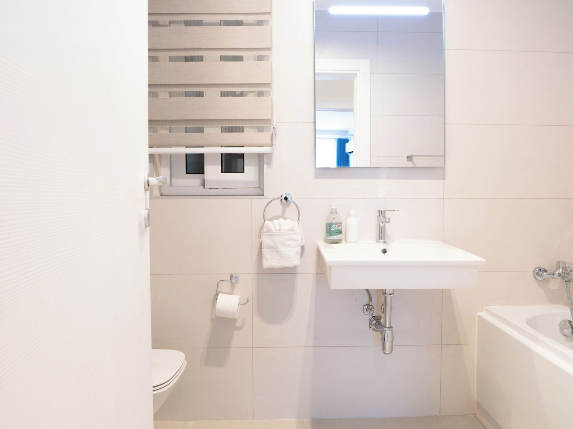 Une salle de bain moderne avec un lavabo blanc, un miroir, des toilettes et une baignoire.