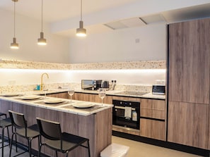 A modern kitchen with a central island, wooden cabinets, and pendant lighting.