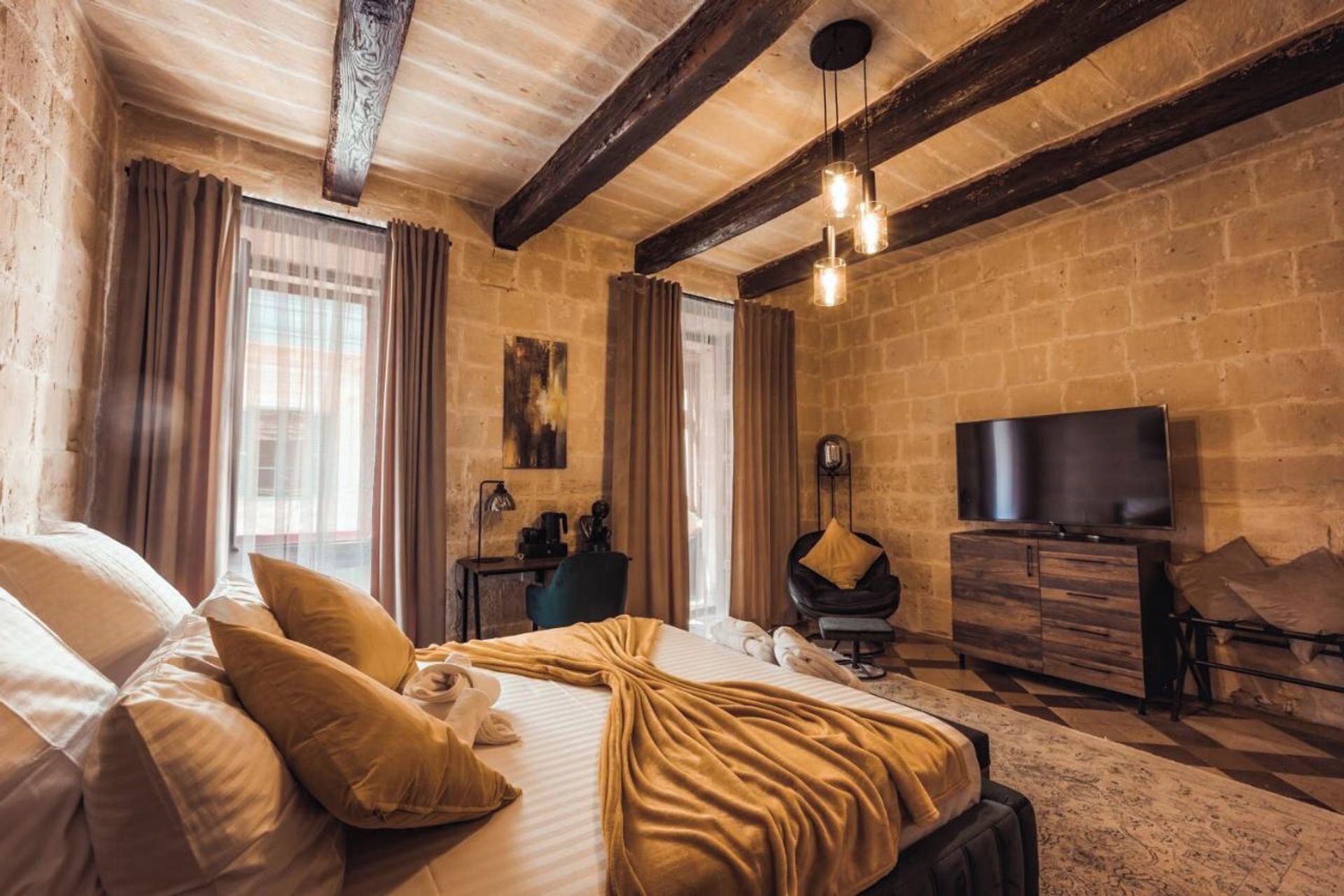 Una camera d'albergo accogliente con un letto grande, una TV a schermo piatto e un comò in legno.