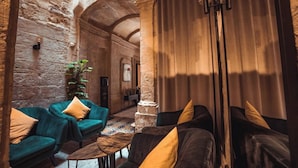 A cozy lounge area with stone walls, a green sofa, a dark sofa, and a small wooden coffee table. - Palazzino Valentina Valletta (Valletta)