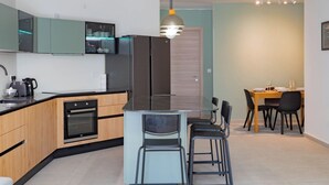 Een moderne keuken met een centraal eiland, inbouwapparatuur en een eethoek met een tafel en stoelen.