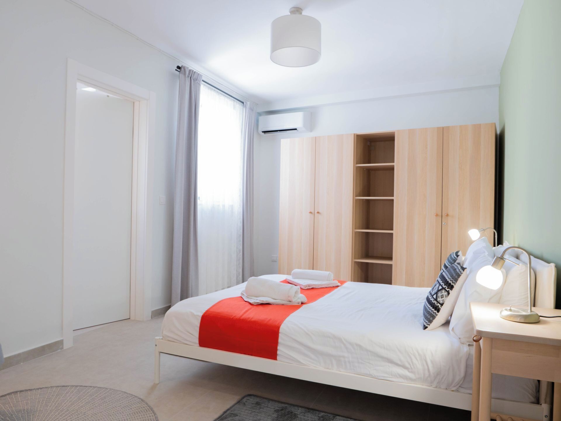 Un dormitorio moderno con cama, mesita de noche con lámpara y armario.