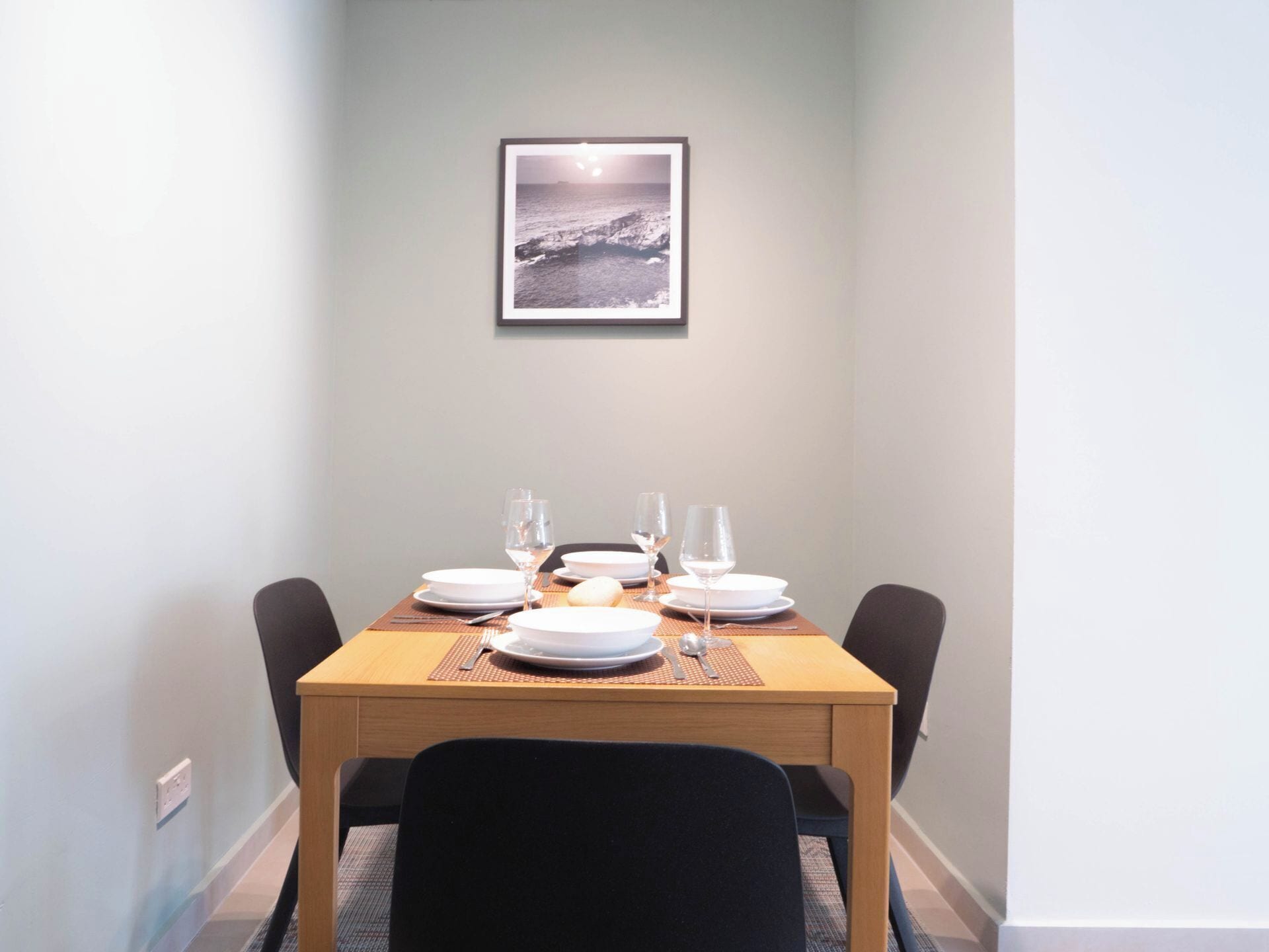 Een eettafel gedekt met borden, glazen en bestek, met daarboven een ingelijste foto.