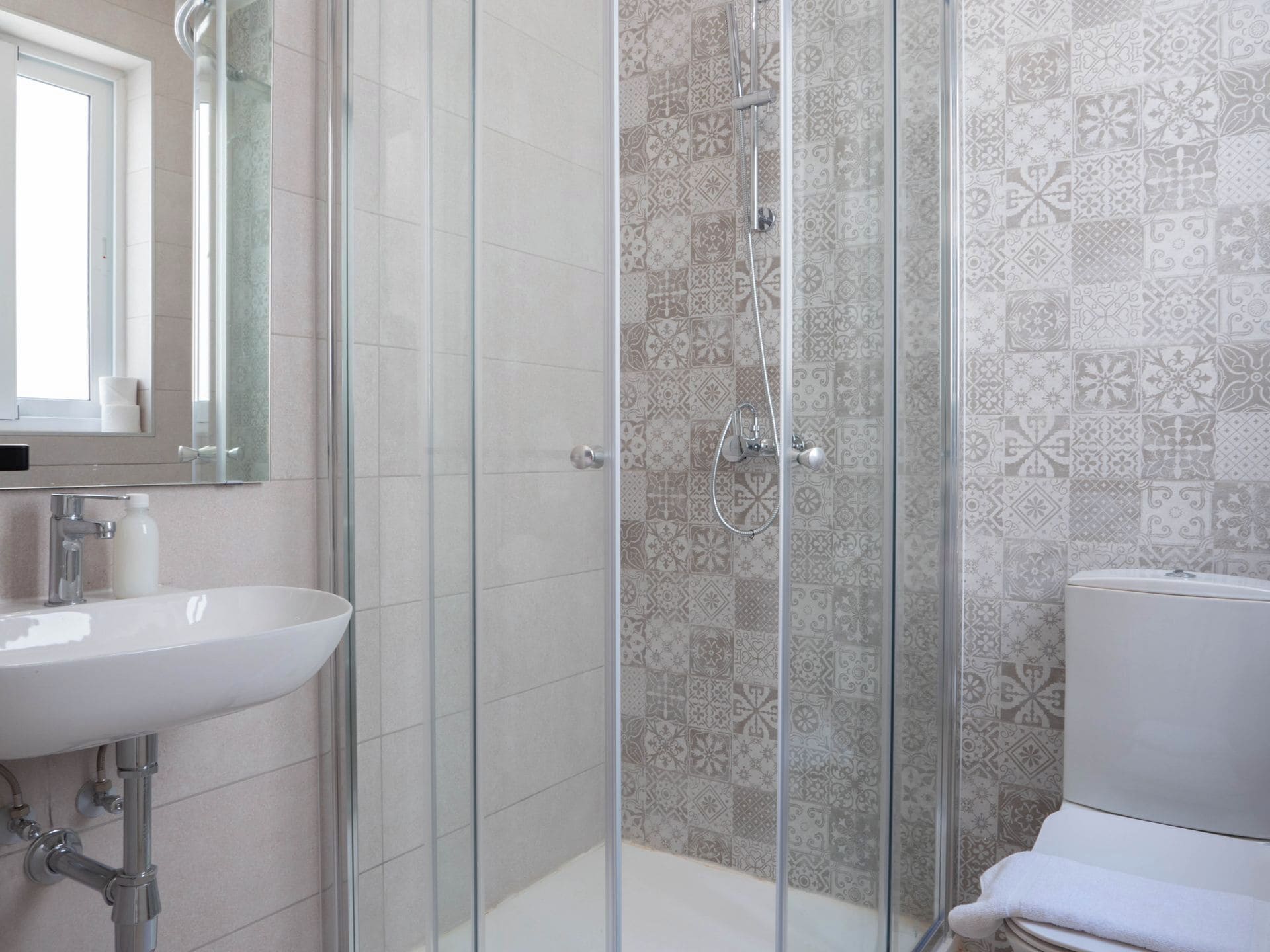 A bathroom with a glass shower enclosure, a sink, and a toilet.