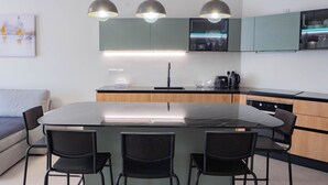 Een moderne keuken met een centraal eiland, zwarte stoelen en hanglampen.