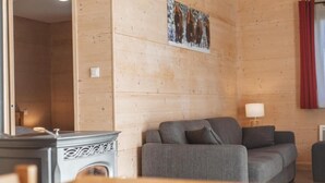 A wooden-paneled room with a sofa, a table, and a lamp. - Les Bouviers (Saint-Paul-le-Froid)