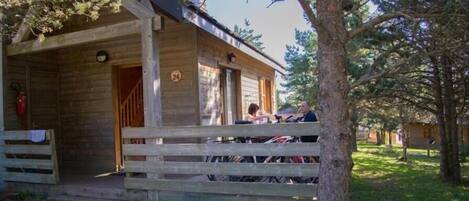 Una cabaña de madera con un porche, un extintor de incendios y un cartel con el número 24.