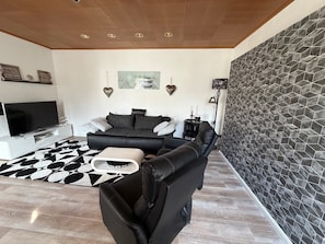 A modern living room with a sofa, a TV, and a patterned rug. - Apartment 'Sterntaler Melsungen' (Melsungen)