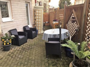A patio with wicker furniture, a table with a white tablecloth, and potted plants. - Apartment 'Sterntaler Melsungen' (Melsungen)