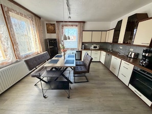 A modern kitchen with a dining area, featuring a built-in oven, microwave, and sink. - Apartment 'Sterntaler Melsungen' (Melsungen)