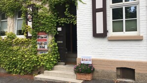 Ein Gebäude mit weißer Fassade, einer schwarzen Tür und einem kleinen Blumenkasten an den Stufen.