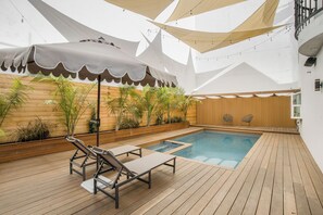 Ein Poolbereich mit Holzboden, Liegestühlen und einer Markise.