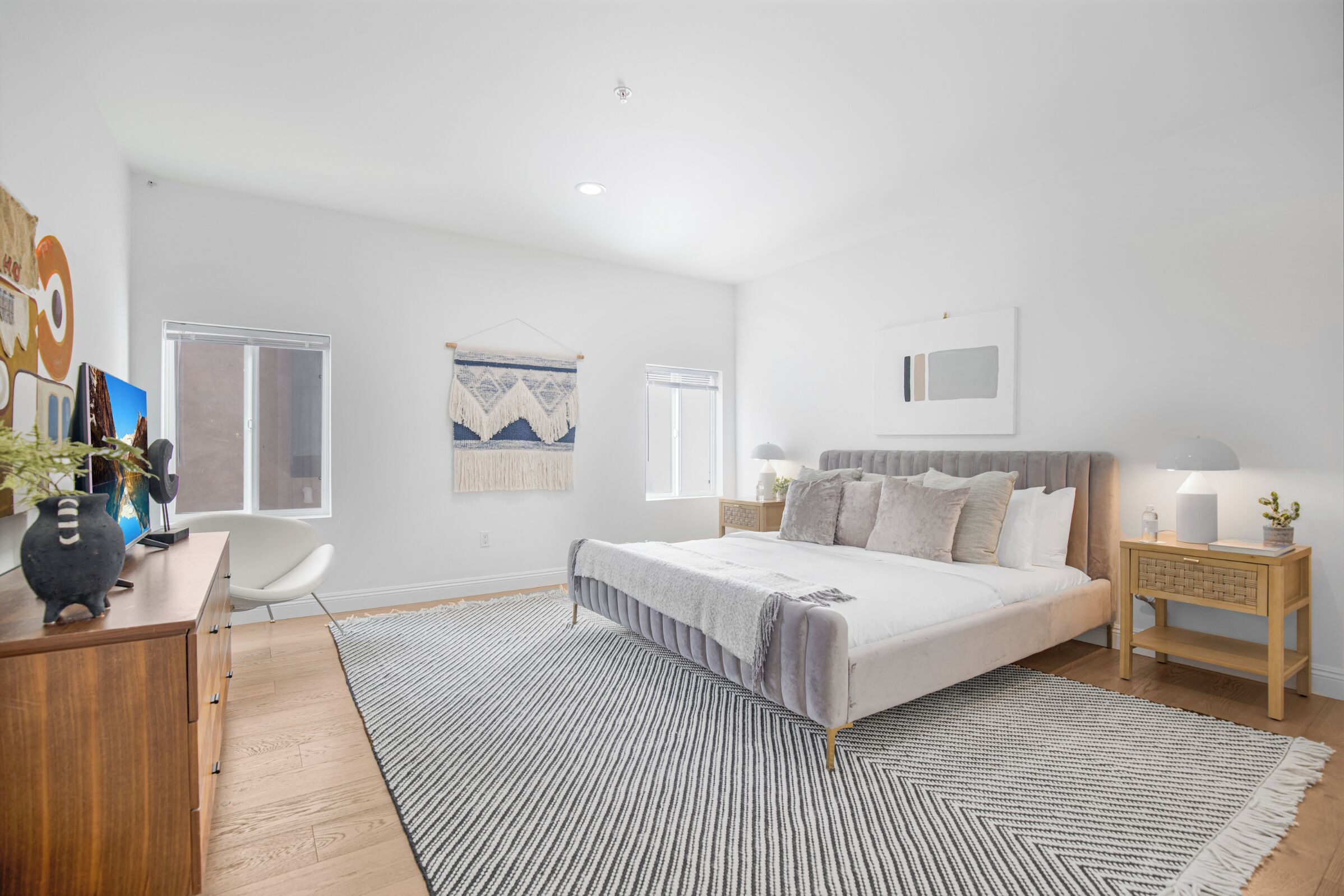Een moderne slaapkamer met een bed, nachtkastjes, een bureau en een stoel.