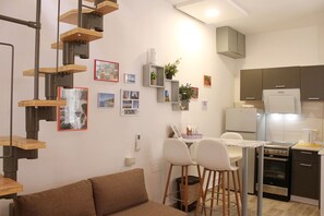 A modern kitchen with a built-in oven, a refrigerator, and a dining area with a table and two chairs. - Klarisa - city center studio with a private terrace (Split)