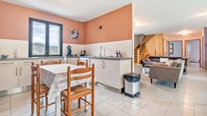 A modern kitchen with a dining area, a staircase, and a living room with a sofa. - Holiday Home “Gite Chez Léontine” with Private Terrace, Wi-Fi and Air Conditioning (Lacave)