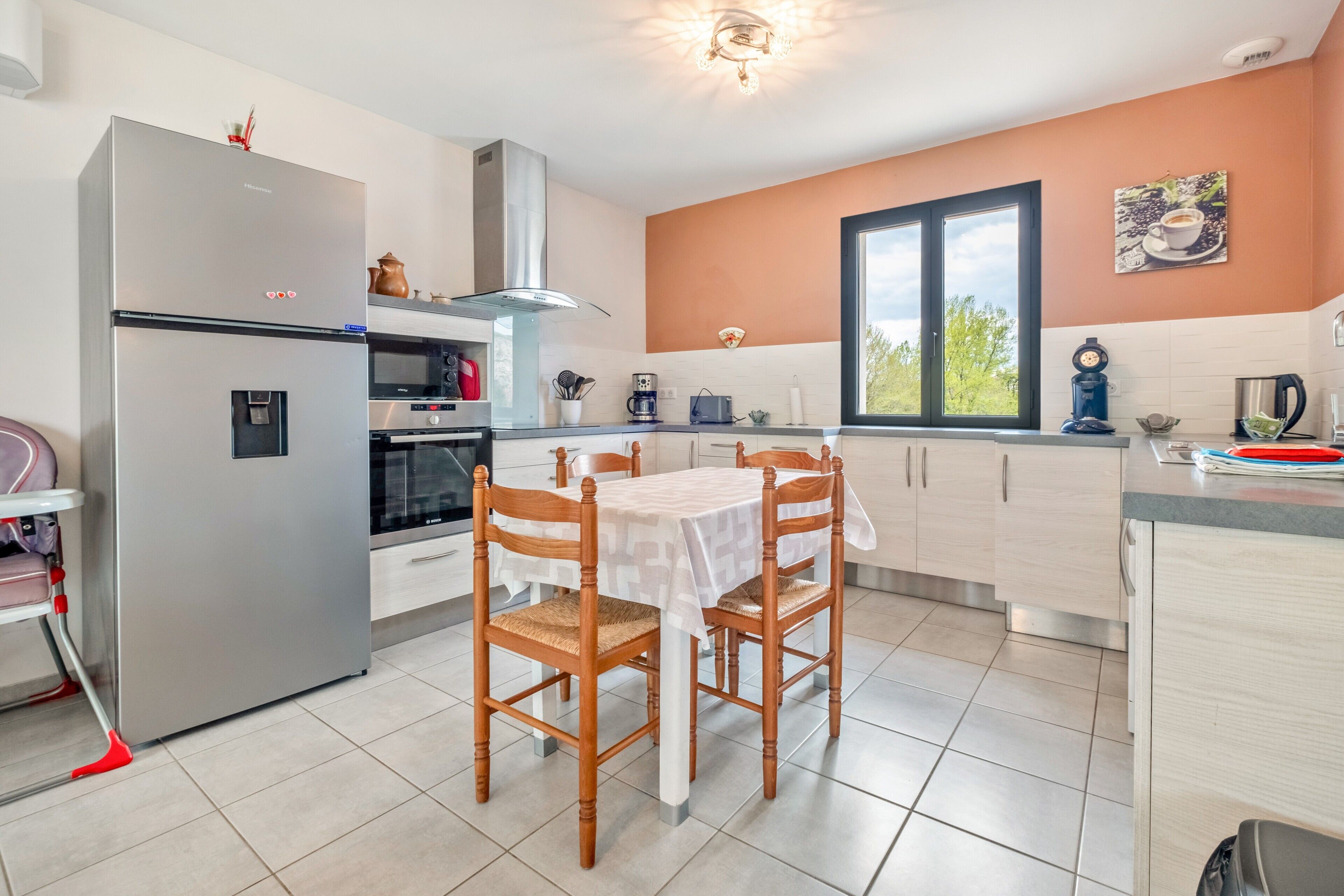 Una cocina moderna con refrigerador, horno y mesa de comedor con sillas.