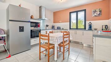 Una cocina moderna con refrigerador, horno y mesa de comedor con sillas.