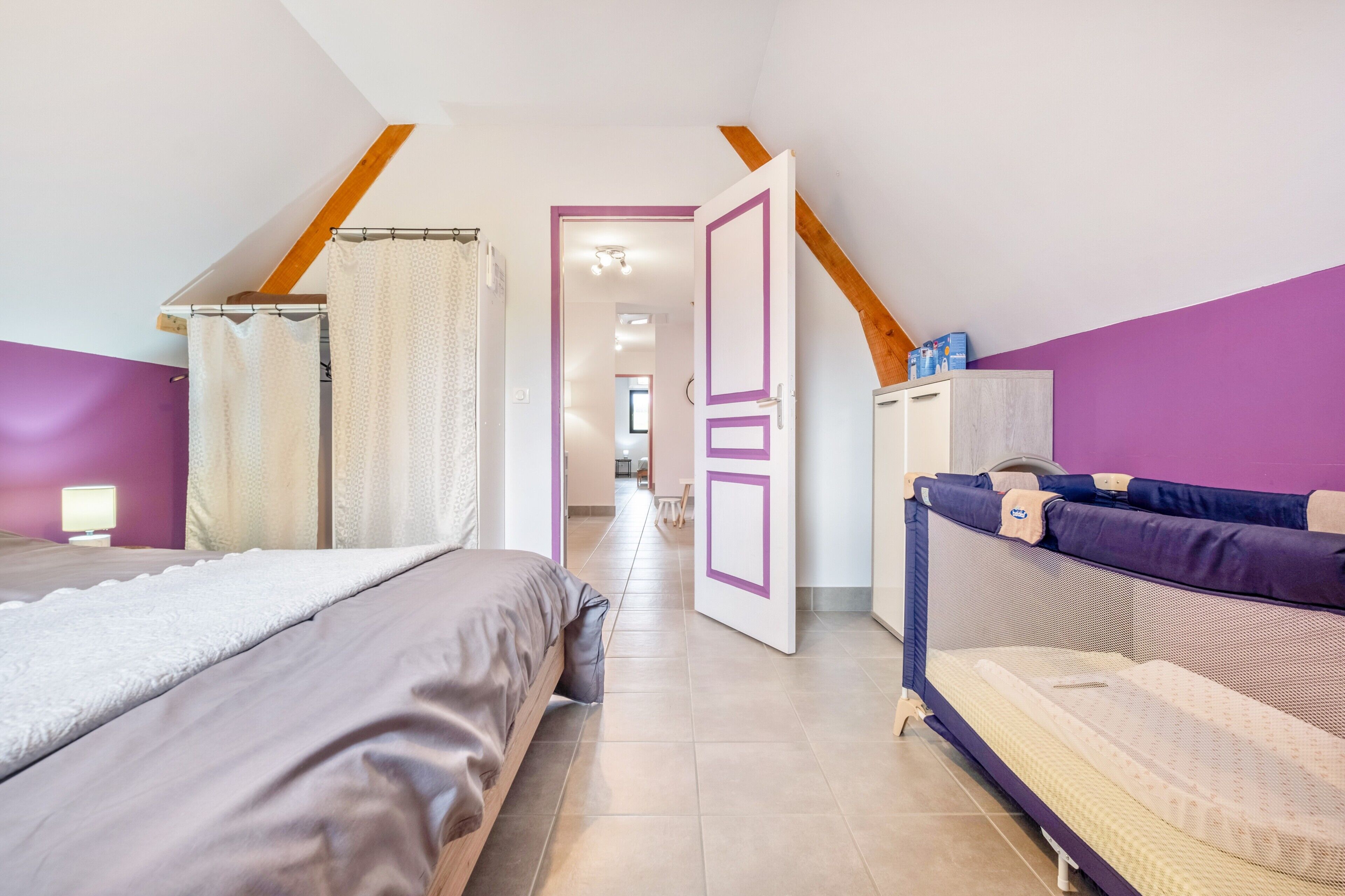 A bedroom with two beds, a wardrobe, and a bathroom visible through an open door.