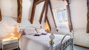 A bedroom with a bed, nightstand, lamp, and a window with curtains.