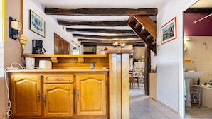 A kitchen with wooden cabinets, a coffee machine, and a stone wall.